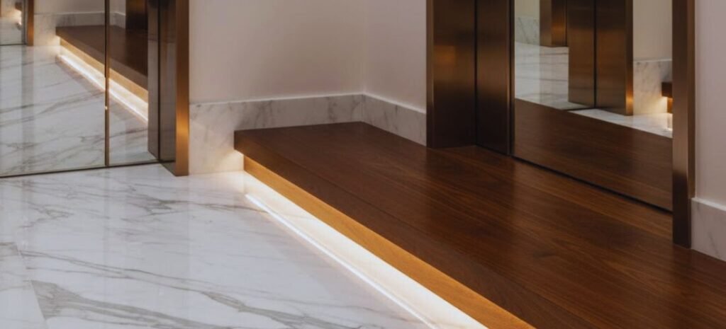 Dettaglio di finiture di pregio: pavimento in marmo chiaro e gradino in legno scuro con illuminazione LED integrata.