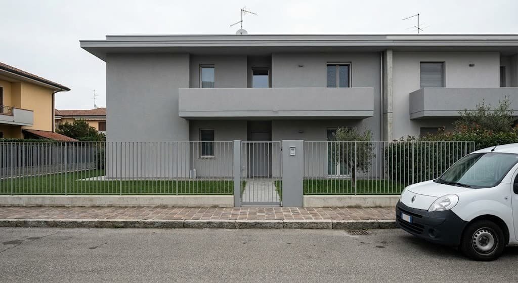 Prospetto di una nuova costruzione residenziale moderna con facciata grigia, recinzione in metallo minimale e cura del verde esterno in provincia di Savona.